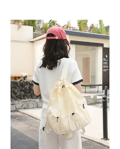 Back view of cream nylon drawstring backpack worn in casual urban setting