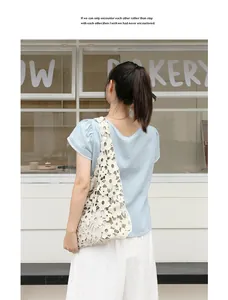 Detailed view of a white floral crochet lace shoulder bag worn by a female model.