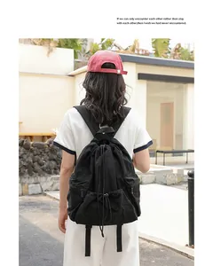 Black casual nylon drawstring backpack with pleated design worn by a model outdoors