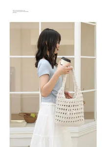 A hand-woven cotton hollow shoulder bag being carried by a model in a trendy cafe setting