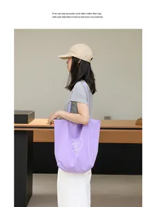 Modelo llevando un bolso tote de nailon morado con estampado de corazón en un entorno minimalista
