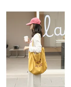 Vue lifestyle urbaine d'un sac cabas en lin jaune avec impression de lettres porté
