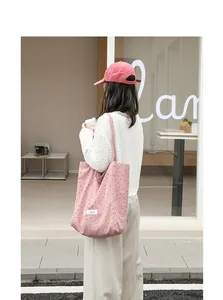Lifestyle detail shot of a pink polka dot nylon tote bag carried by a model outdoors.