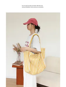 Detalle de un bolso tote de lona a rayas amarillas y blancas de gran capacidad en modelo