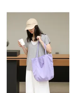 Bolso tote de nailon con rayas moradas llevado por una modelo en un ambiente interior moderno.