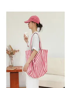 Foto de estilo de vida de un bolso tote de lona a rayas rosas y blancas con modelo