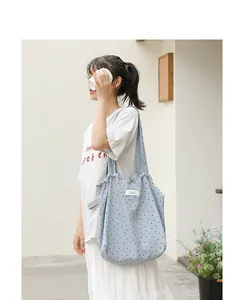 Detalle del bolso tote de lona con lunares azul claro y diseño plisado con cordón