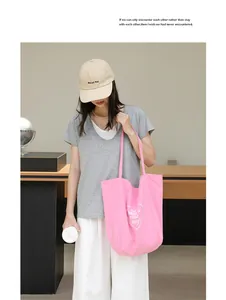 Vista detallada del bolso tote de nailon rosa con estampado de corazón y eslogan en modelo