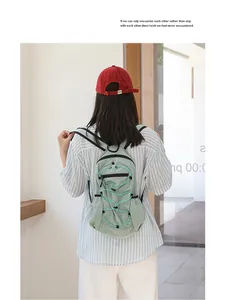 Detail view of a light green checkered nylon backpack carried by a model in casual wear.