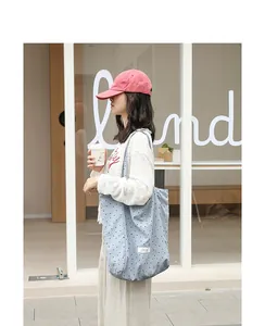 Close-up of a light blue nylon tote bag with black polka dots used in a street setting