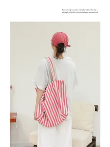 Modelo con un gran bolso de lona a rayas rosas y blancas en un interior minimalista