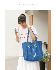 Dettaglio lifestyle di una grande borsa tote in tela blu con stampa STOW IT HERE