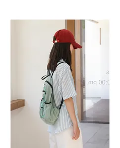 Side-back view of a light green plaid nylon backpack with drawstring on a model