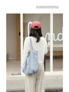 Detail view of a light blue polka dot nylon tote bag carried by a model in casual outfit