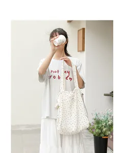 Foto de estilo de vida de un bolso tote de lona de lunares con cordón ajustable