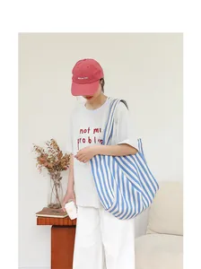 Imagen detallada de un bolso de lona a rayas azules y blancas con un atuendo casual
