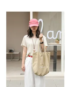 Asian model carrying a beige Japanese casual nylon tote bag with white letter print outdoors