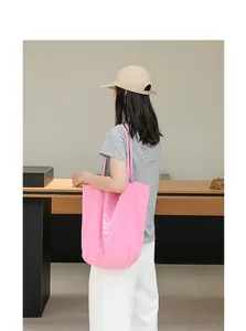 Vista detallada de un bolso tote de nailon rosa con estampado de corazón y texto