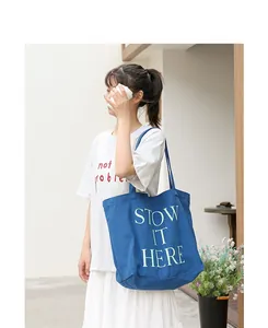 Borsa tote in tela blu con stampa STOW IT HERE indossata da una modella