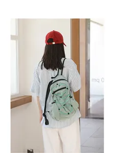 Back view of a model wearing a light green checkered nylon backpack with bungee cord