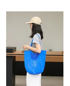 Bolso tote casual de nailon azul con estampado de corazón y mensaje en modelo.