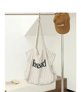 Close-up of a striped canvas tote bag with Bread letter print hanging on a metal rack