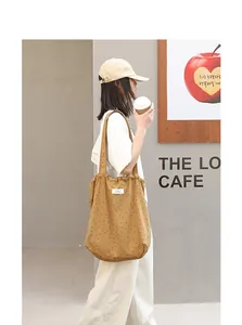 Modelo con un bolso tote de lona marrón con lunares y cordón dentro de un café