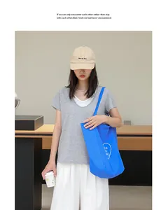 Bolso tote casual de nailon azul con estampado de corazón, llevado por modelo en estudio.