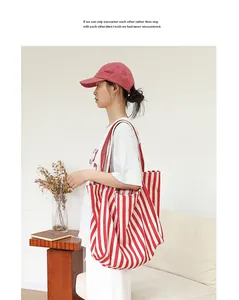 Bolso tote grande de lona a rayas rojas y blancas con un atuendo y decoración minimalistas.