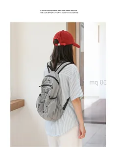 A model wearing a grey grid patterned nylon backpack with casual pleated design and bungee cords