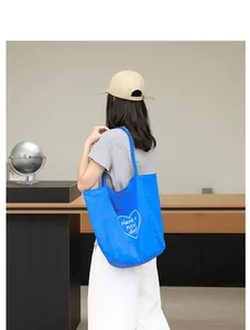 Primer plano de un bolso tote de nailon azul con un estampado de corazón blanco.