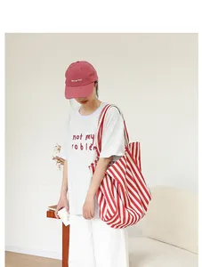 Detalle de un gran bolso tote de lona a rayas rojas y blancas con un atuendo informal.