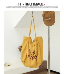 Détail d'un sac cabas en lin jaune avec imprimé lettres bordeaux suspendu à un crochet