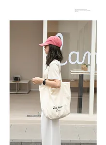 Minimalist cream nylon tote bag with letter print shown in a lifestyle setting