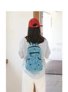 Lightweight blue grid nylon backpack with adjustable bungee cord detail on model