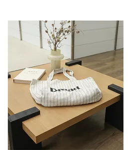 Close-up of striped cotton linen tote bag with Bread lettering on a wooden table