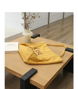 Vue détaillée d'un sac cabas en lin jaune avec imprimé lettre sur une table en bois chic