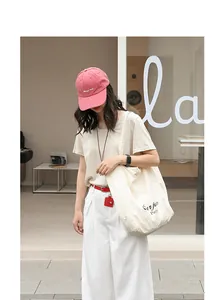 Lifestyle view of a casual white nylon tote bag with black letter embroidery