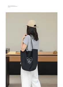 Vista trasera de una modelo con un bolso tote de nailon negro con estampado de corazón.