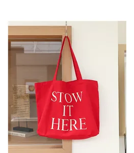 Dettaglio ravvicinato di una borsa tote in tela rossa con stampa bianca Stow It Here