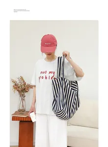 Modelo asiática con un bolso tote de lona a rayas azules y blancas