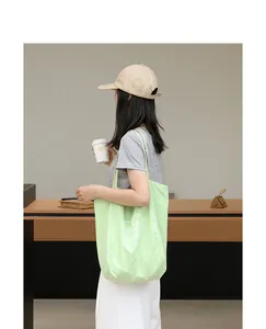 Detalle del bolso tote de nailon verde claro con estampado de corazón en la modelo
