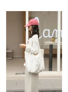 Detailed side profile of woman carrying a stylish cream canvas tote bag with black polka dots