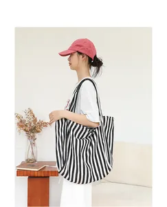 Modelo asiática con bolso tote de lona a rayas en un entorno minimalista.