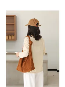 Vista posteriore di donna con grande borsa hobo in camoscio marrone e tracolla annodata