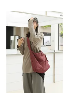 Burgundy waffle textured canvas crossbody bag shown on model in cafe setting