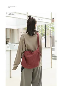 Red textured grid crossbody messenger bag with knot detail strap worn by model
