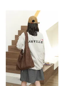 Lifestyle shot of a brown suede hobo bag with drawstring detail worn by a model