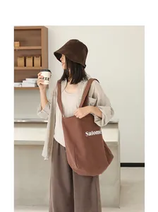 Stylish brown linen tote bag with Salomé letter print worn by a model in a cafe