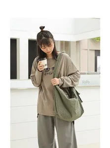 Close-up detail of a green checkered nylon messenger bag worn by an Asian fashion model